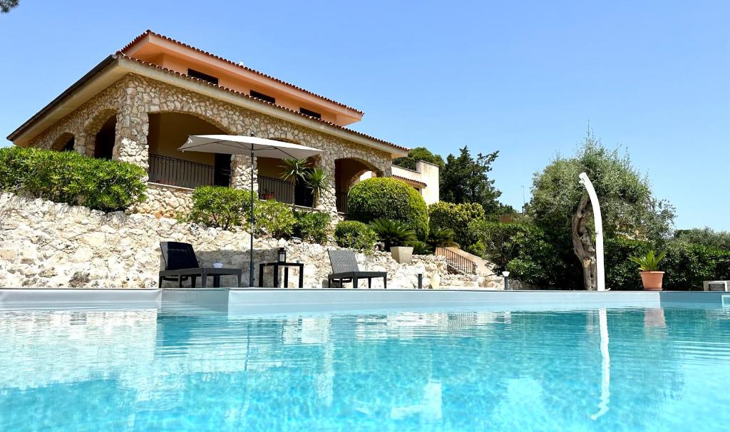 Casa con piscina con 2 sillas y sombrilla en Villa Rina, en Avola