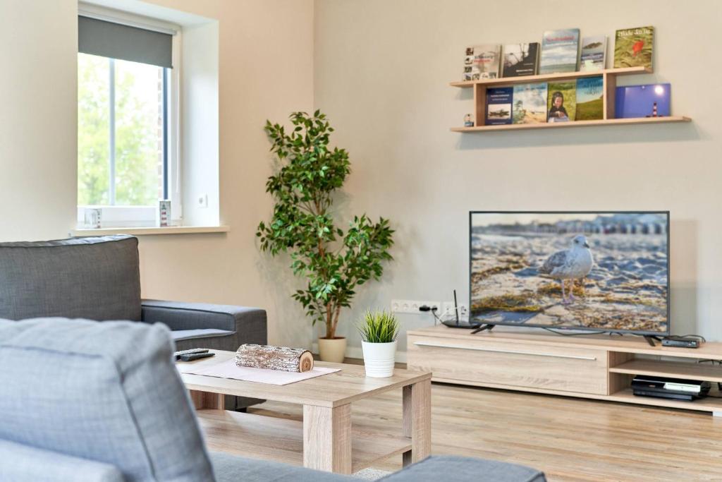 ein Wohnzimmer mit einem TV und einem Tisch in der Unterkunft Der Wattläufer in Ockholm