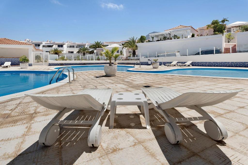 ein Paar Stühle und ein Tisch neben einem Pool in der Unterkunft Holiday Valley Blue Ocean B2 in Adeje