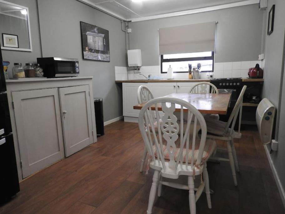 una cucina e una sala da pranzo con tavolo e sedie di Skylark Shepherds Hut a Royal Tunbridge Wells