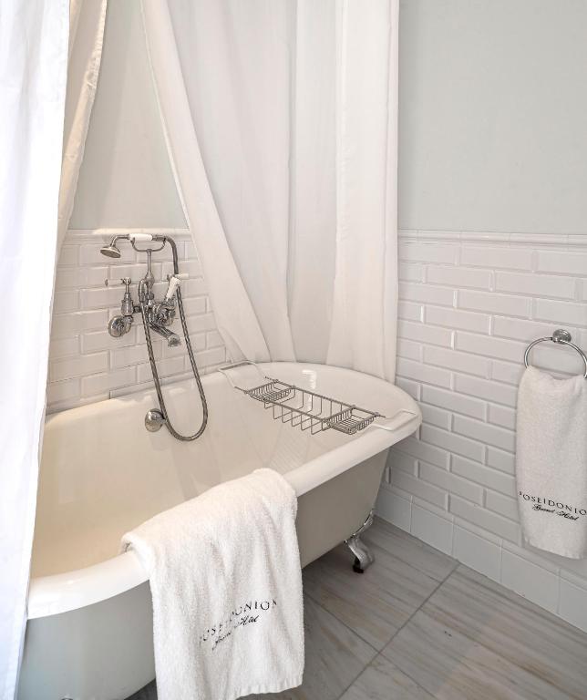 a white bathroom with a tub and a shower at Poseidonion Grand Hotel in Spetses