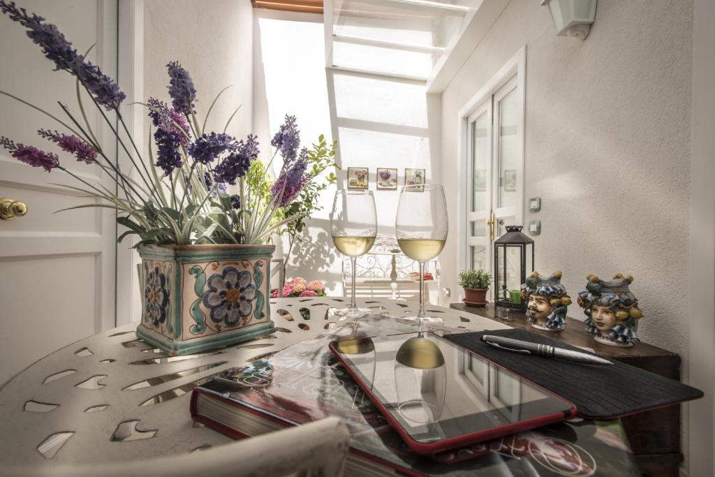 stół z dwoma kieliszkami wina i wazon z kwiatami w obiekcie Pane Amore e Marmellata w mieście Palermo