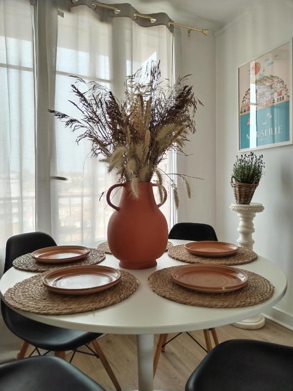 a white table with plates and a vase on it at Massilia Calling love Appartement de standing 8 personnes Marseille proche métro parking facile in Marseille