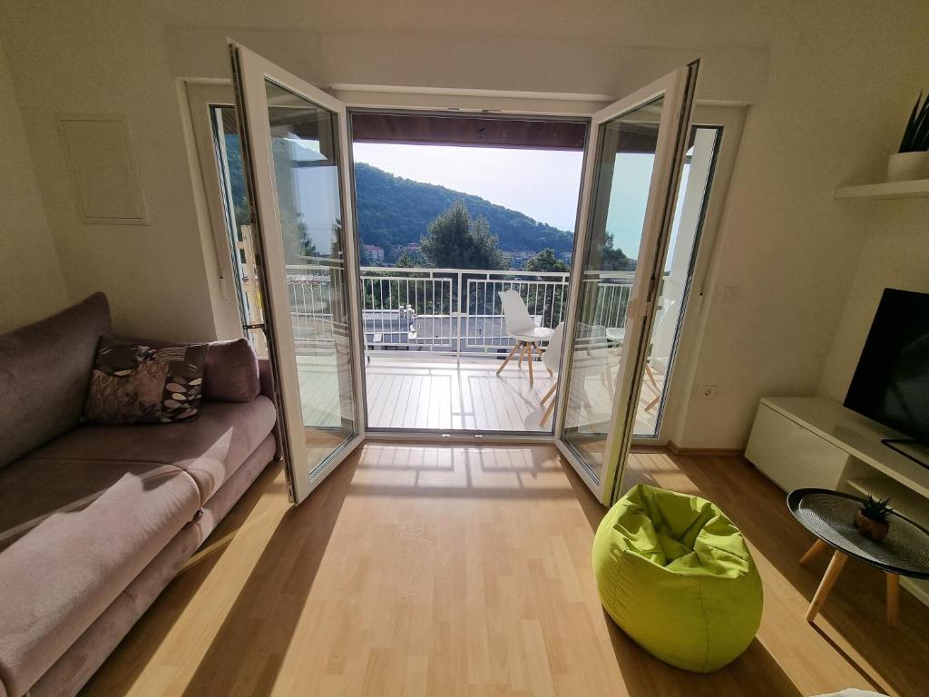 a living room with a couch and a sliding glass door at Seaview Apartment Luka with free private parking in Mošćenička Draga in Mošćenička Draga
