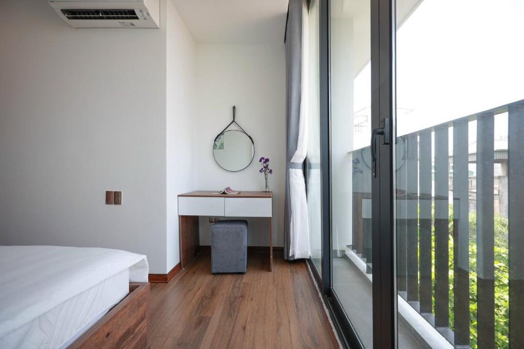 Schlafzimmer mit einem Bett und einem Schreibtisch mit einem Spiegel in der Unterkunft Sweethome 121 Yen Phu Westlake Apartment in Hanoi