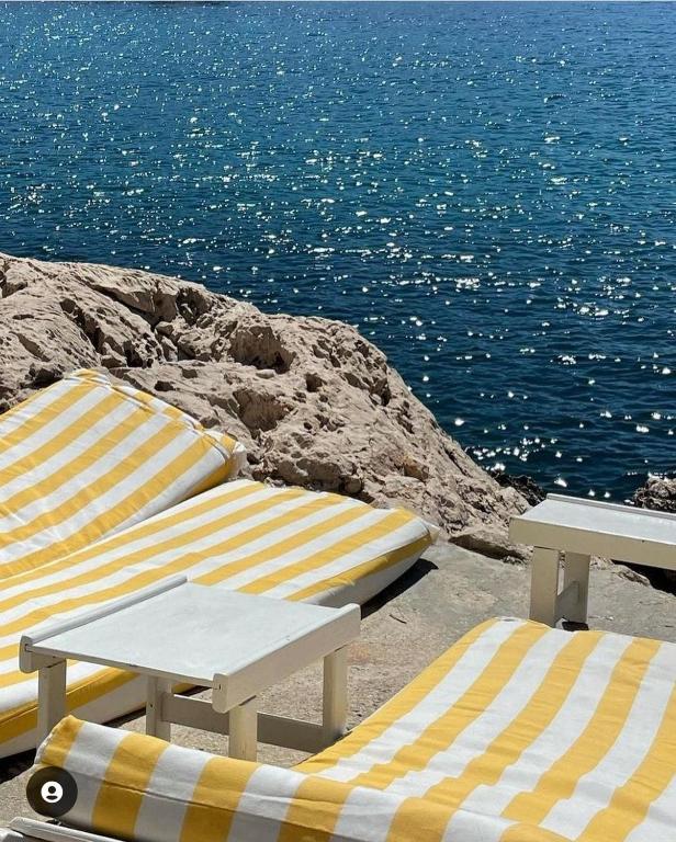 two beach umbrellas and chairs sitting on the beach at Massilia Calling love Appartement de standing 8 personnes Marseille proche métro parking facile in Marseille