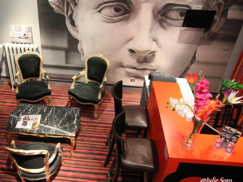 a large statue of a face in a room with chairs at Hôtel Latino Reims Centre in Reims