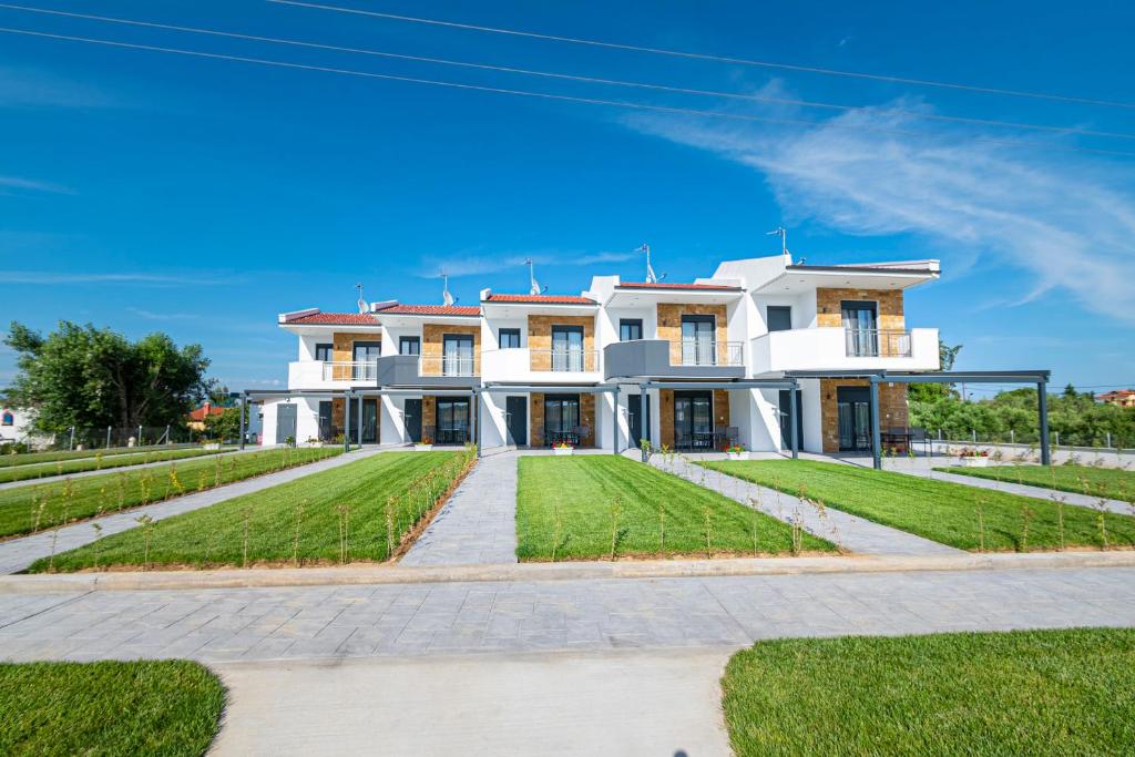 a large white house with a green lawn at Chryssis Village by Travel Pro Services - Nea Potidaia Halkidiki in Nea Potidaea