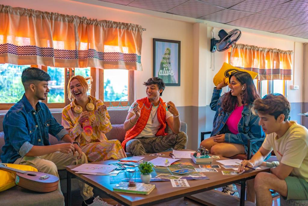 um grupo de pessoas sentadas à volta de uma mesa em The Hosteller Mussoorie, Mall Road em Mussoorie