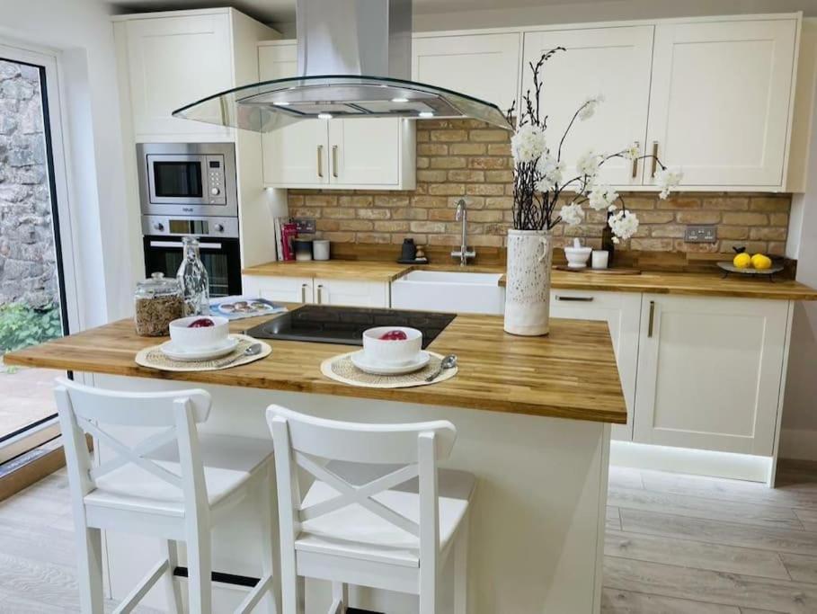 cocina con encimera de madera y armarios blancos en Charming Cottage close to M4 Bridgend, en Bridgend