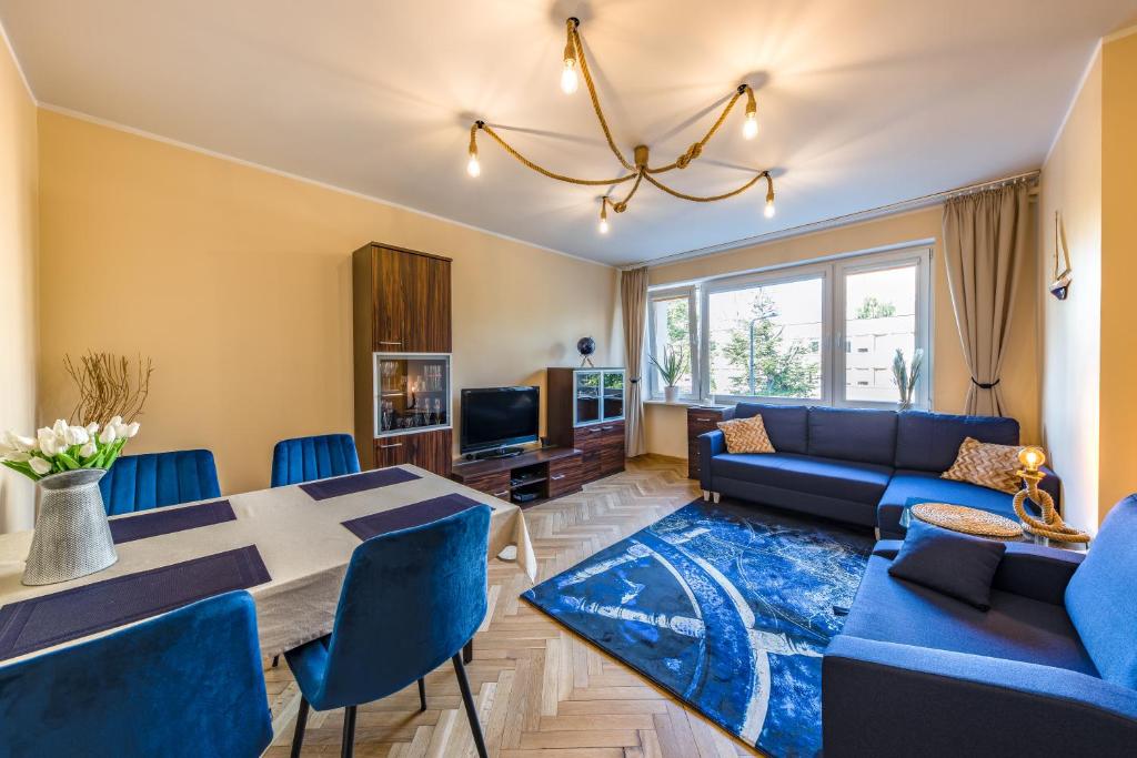 - un salon avec un canapé bleu et une table dans l'établissement Bosman Apartment Gdynia, à Gdynia
