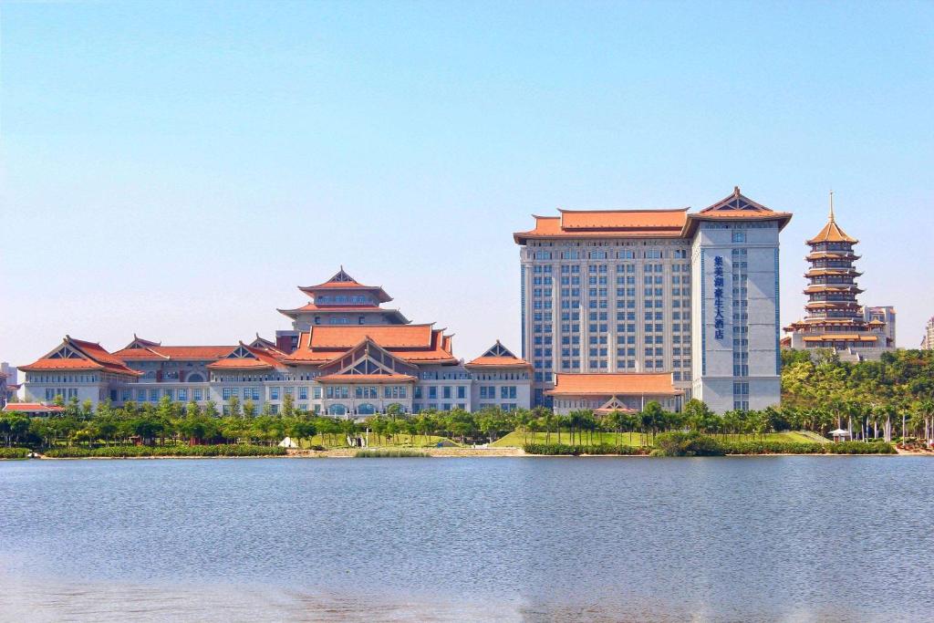 a group of buildings next to a body of water at Howard Johnson by Wyndham Jimei Lake Plaza Xiamen in Xiamen