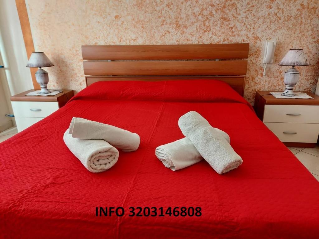 a bedroom with a red bed with towels on it at Appartamento Achiazza Scala dei Turchi in Realmonte