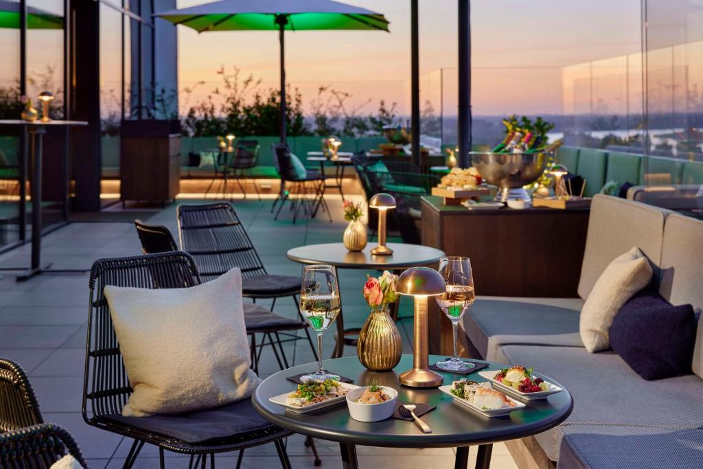 a restaurant with two tables with food and wine glasses at Lindner Hotel Dusseldorf Seestern, part of JdV by Hyatt in Düsseldorf