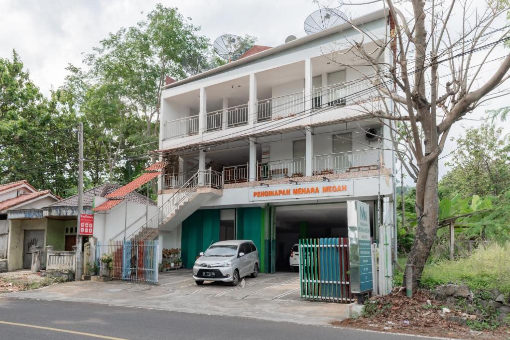 a building with a car parked in front of it at RedDoorz Syariah at Pantai Pelabuhan Ratu in Sukabumi