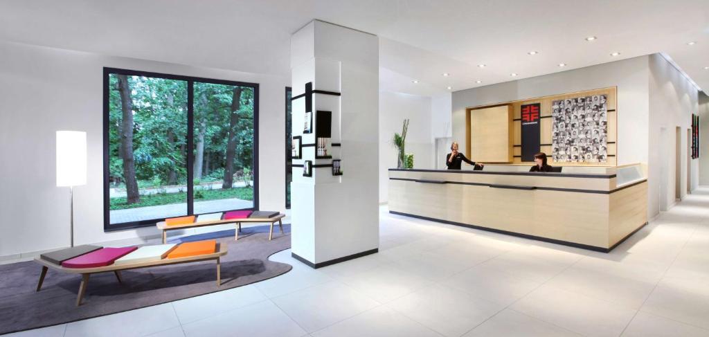 a lobby with a reception desk and benches and windows at Lindner Hotel Frankfurt Sportpark, part of JdV by Hyatt in Frankfurt/Main