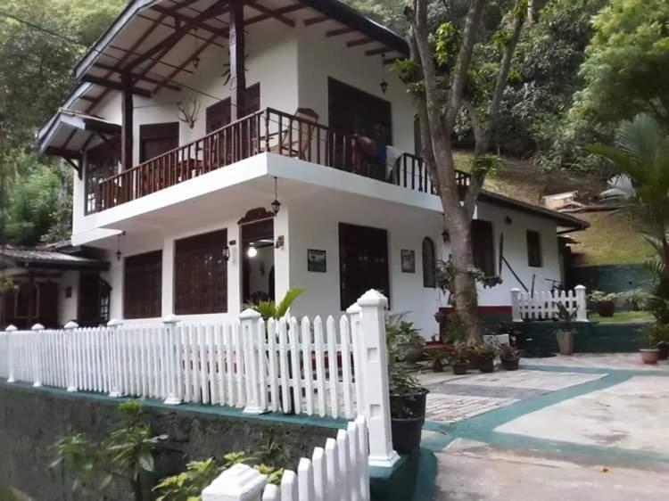 a white house with a white picket fence at Villa25 Homestay free pick up from the centre in Kandy