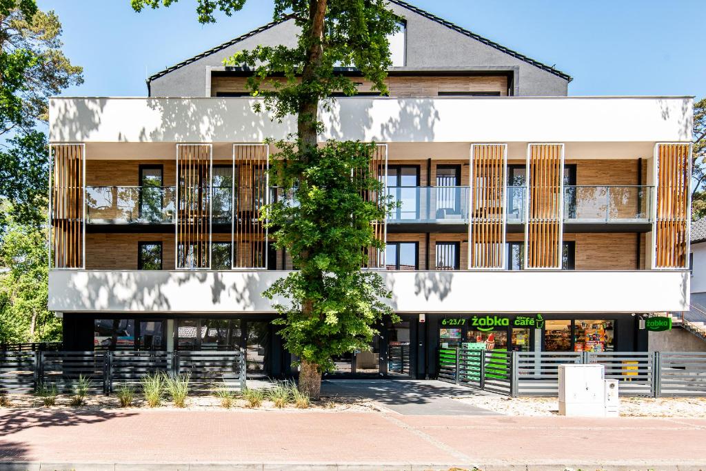 un edificio con un albero di fronte di Apartamenty na Wydmach a Pobierowo