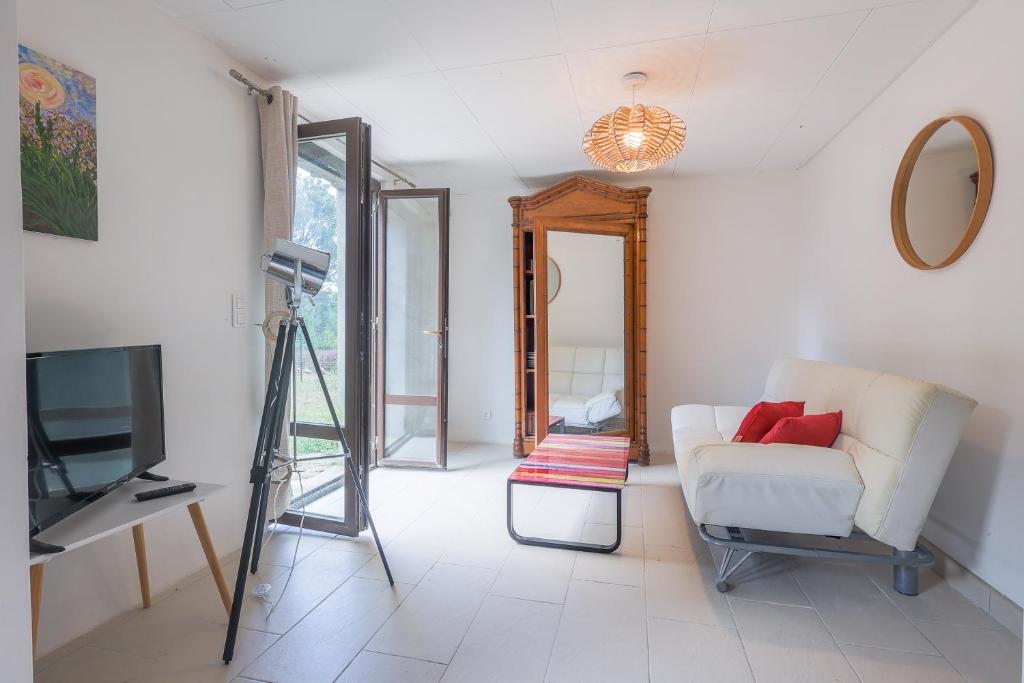 a living room with a white couch and a tv at Calenzana Trè - Appt avec piscine partagée in Calvi