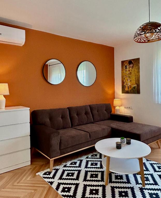ein Wohnzimmer mit einem braunen Sofa und 2 Spiegeln in der Unterkunft Victoria Apartment Skopje in Skopje