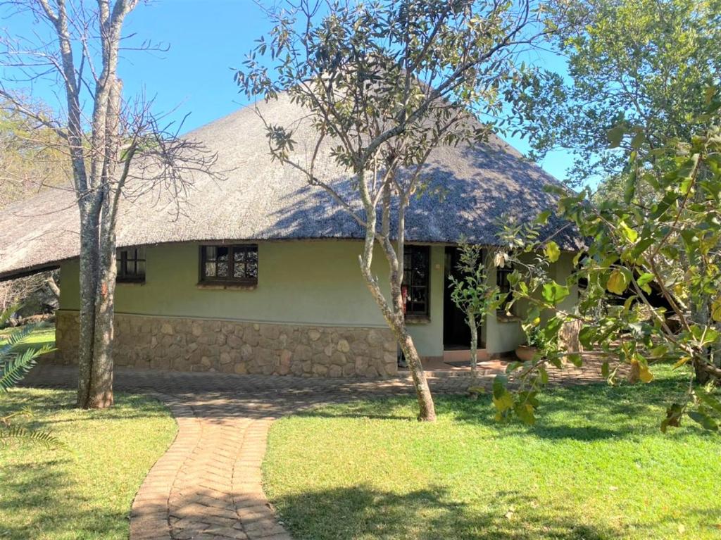 une maison verte avec un mur en pierre dans l'établissement Family Lodge in Natural African Bush - 2115, à Bulawayo