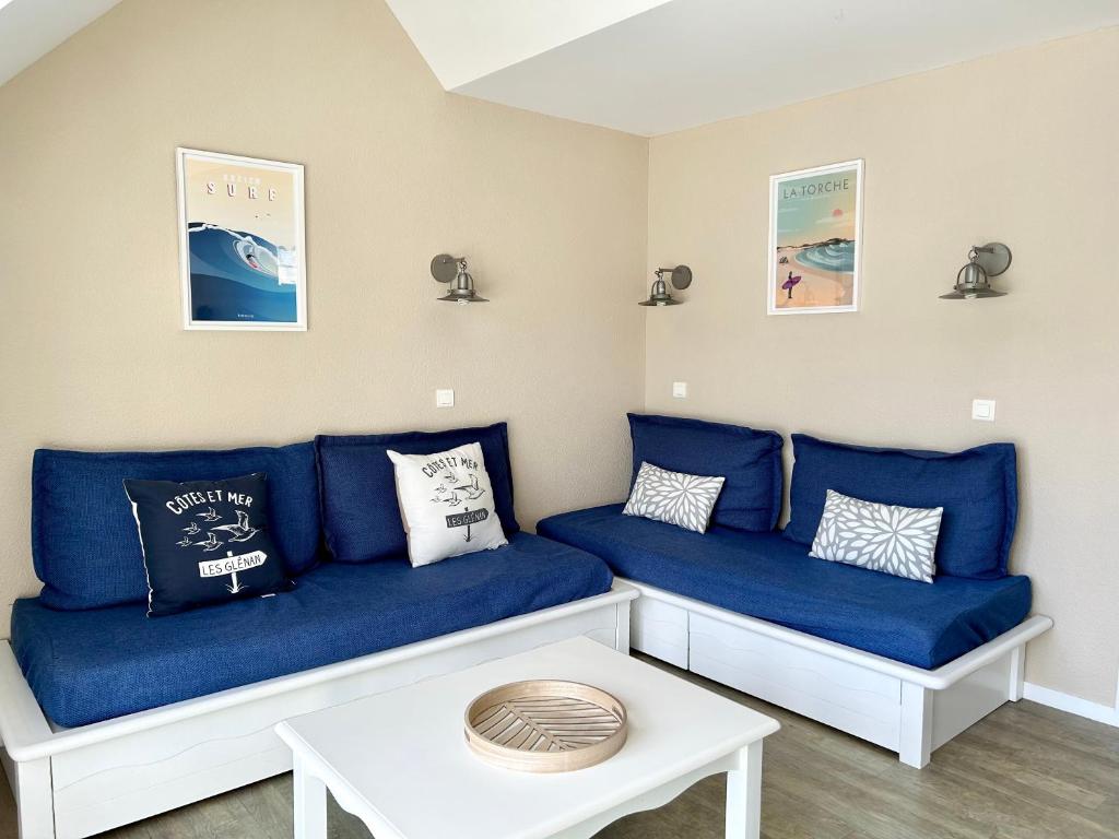 - un salon avec des canapés bleus et une table dans l'établissement Appartement en duplex front de mer, Cap Coz, à Fouesnant
