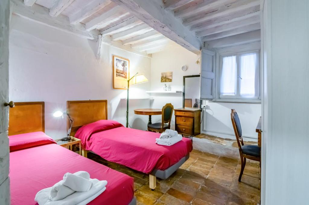 a room with two beds and a desk and a table at Appartamento Valbona nel cuore di Urbino in Urbino
