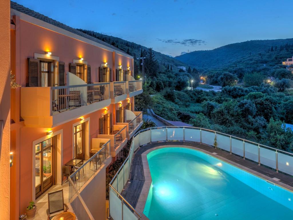 a hotel with a swimming pool in front of a building at Fiscardo Bay Hotel in Fiskardo