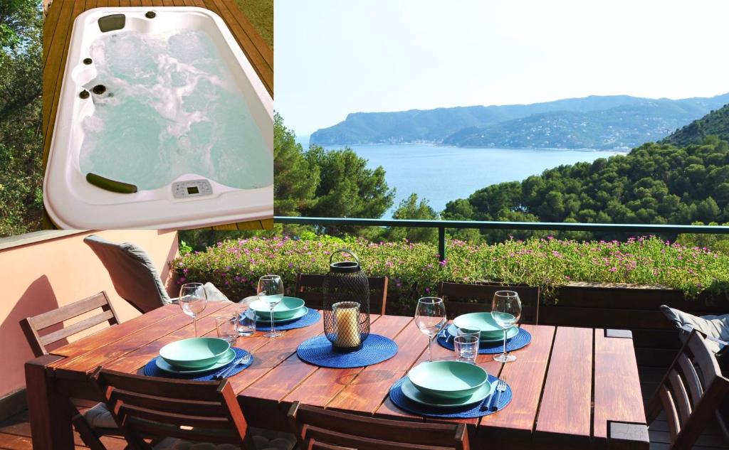 een houten tafel met stoelen en uitzicht op een meer bij Una spettacolare vista mare - Casa con Jacuzzi in Bergeggi