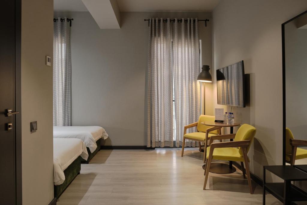 タシュケントにあるSapiens Hotelのベッド2台、テーブルと椅子が備わるホテルルームです。