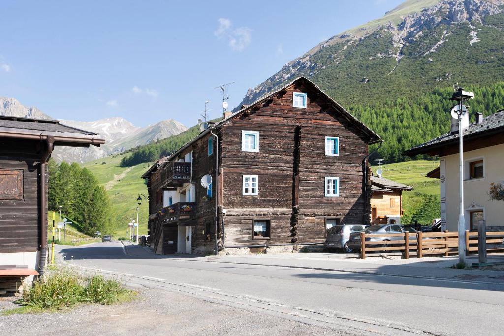 um grande edifício de madeira com uma montanha ao fundo em Casa Valentina em Livigno