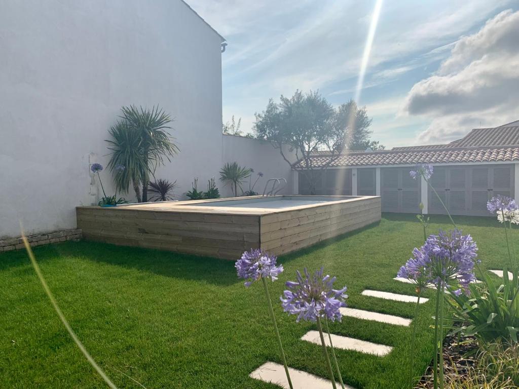 un patio trasero con piscina y flores púrpuras en CAP O SUD grande maison avec Piscine à St Martin de Ré, en Saint-Martin-de-Ré