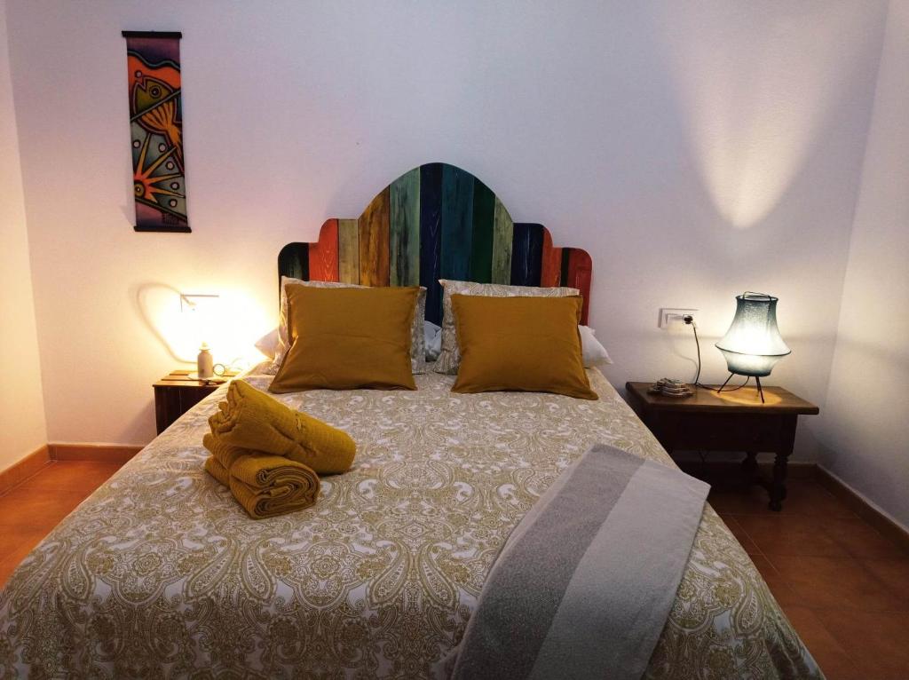 Los Caños de La Casa Viva في فيليز بلانكو: غرفة نوم مع سرير كبير مع وسائد ملونة