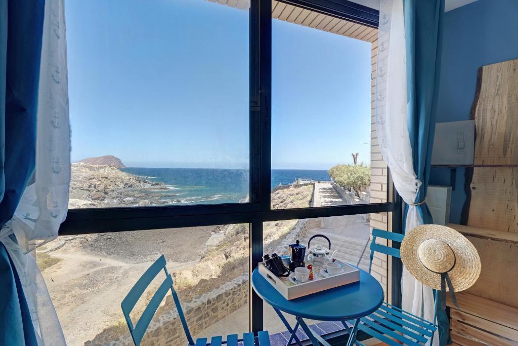 een kamer met een tafel en stoelen en uitzicht op de oceaan bij Los Abrigos oceano al alba wifi in Los Abrigos