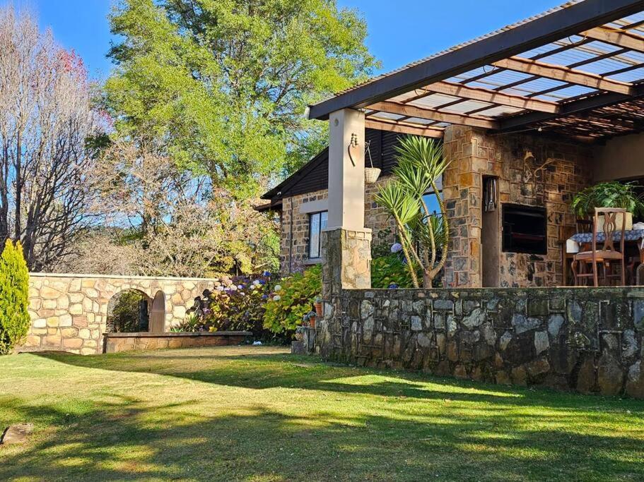 ein Steinhaus mit einer Steinmauer und einer Pergola in der Unterkunft Stone Cottage in Dullstroom