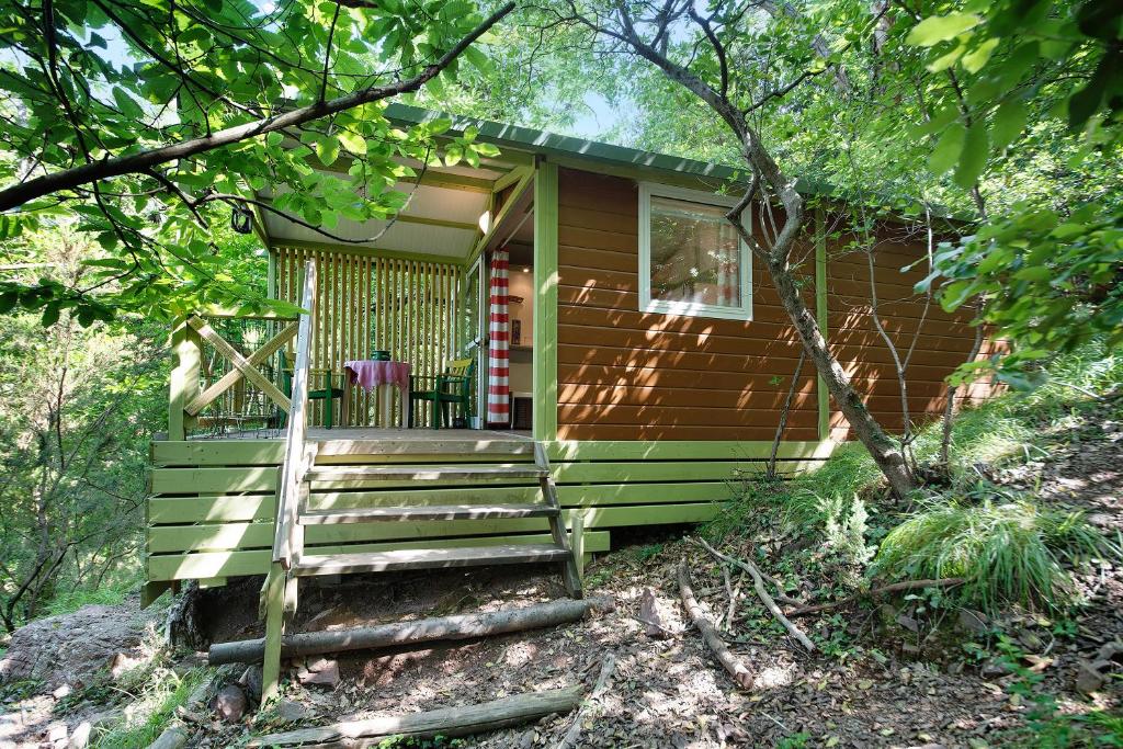 uma pequena cabana verde com um alpendre na floresta em chalet nel bosco em Casarza Ligure