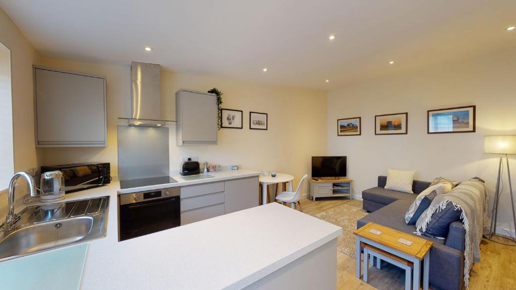 a kitchen and a living room with a couch at Texel Barn in Witney