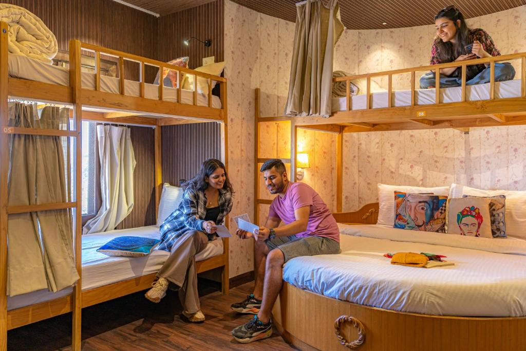 a man and woman sitting in a room with bunk beds at ArtBuzz Mussoorie in Mussoorie