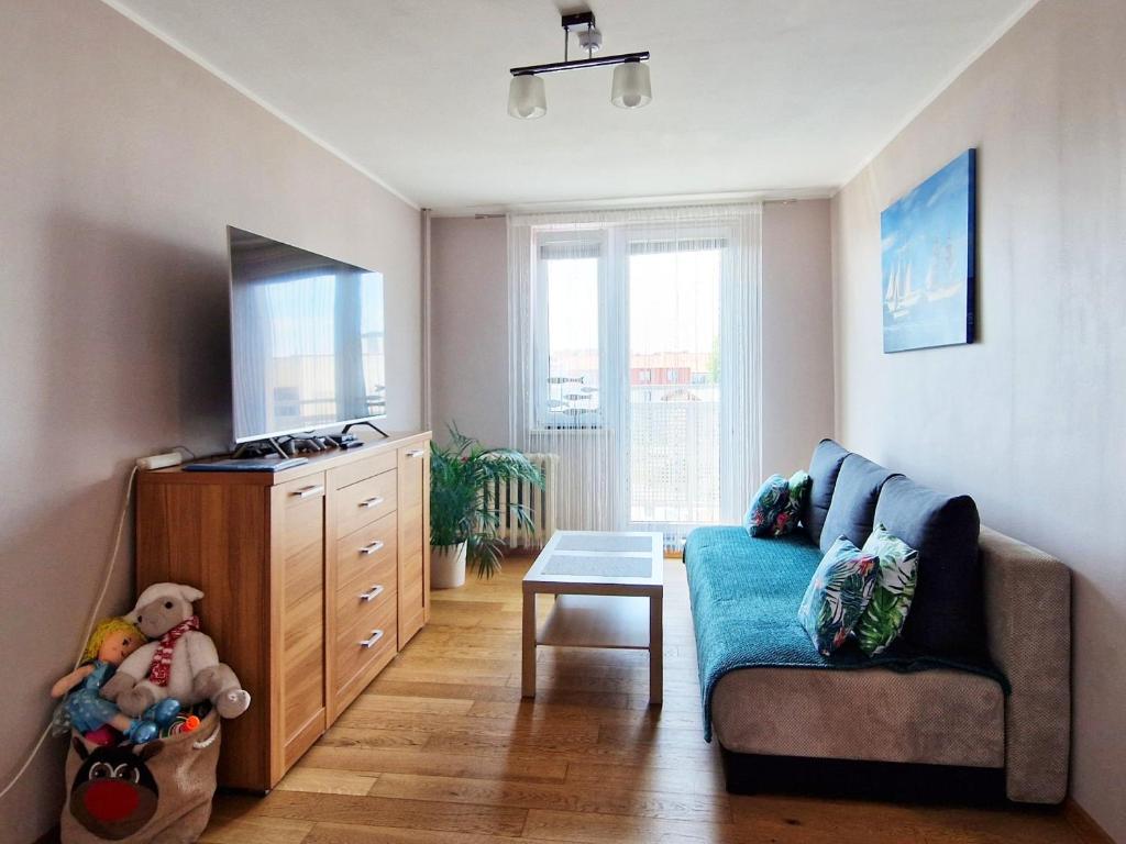 a living room with a blue couch and a dresser at Wicher Hel - mieszkanie blisko centrum in Hel