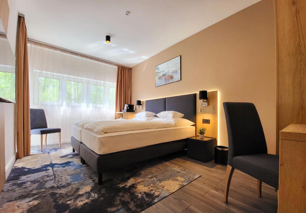 a bedroom with a large bed and a chair at Villa Bauhaus Wellness Apart-Hotel in Siófok