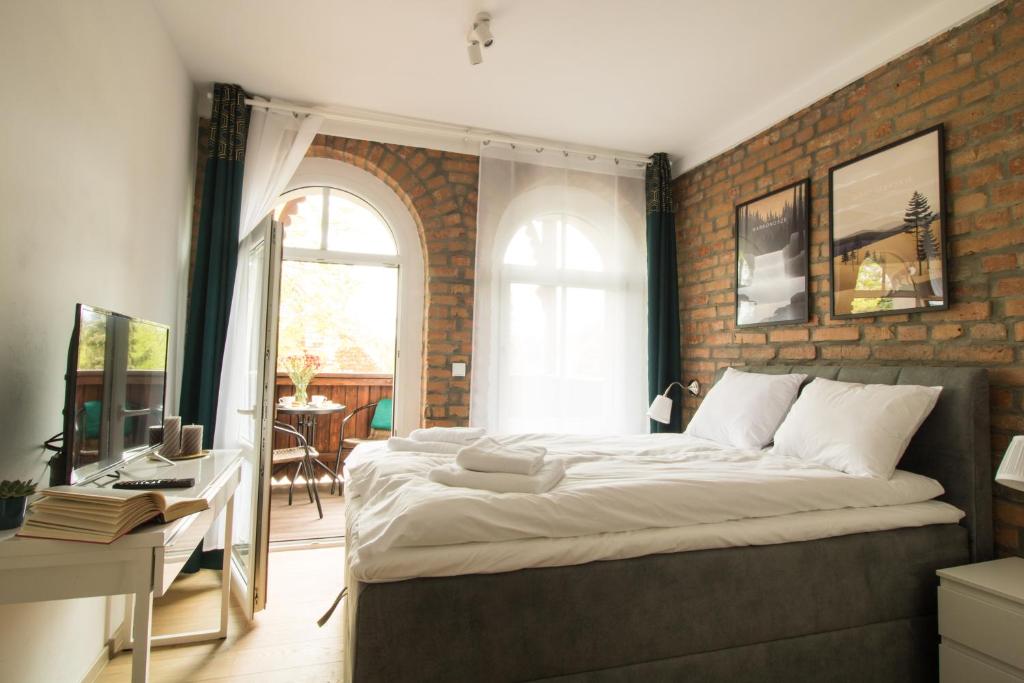 a bedroom with a large bed and a brick wall at Apartamenty Dębowa 3 in Polanica-Zdrój