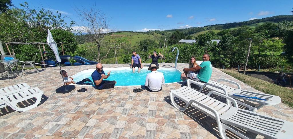 um grupo de pessoas sentadas ao redor de uma piscina em Recanto das Acácias em Guararema