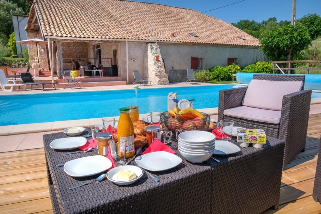 einen Tisch mit Essen darauf neben einem Pool in der Unterkunft Le Domaine de Stellac in Castelmoron-sur-Lot