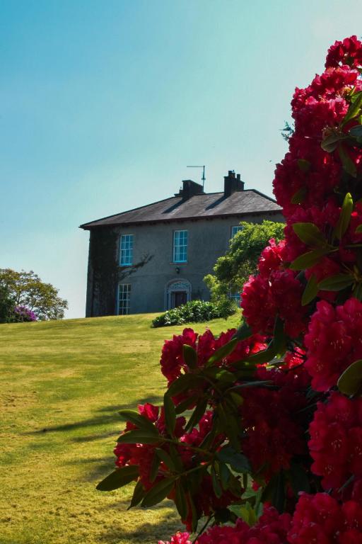 an old house with pink flowers in front of it at Willowbank House & Farm in Keady