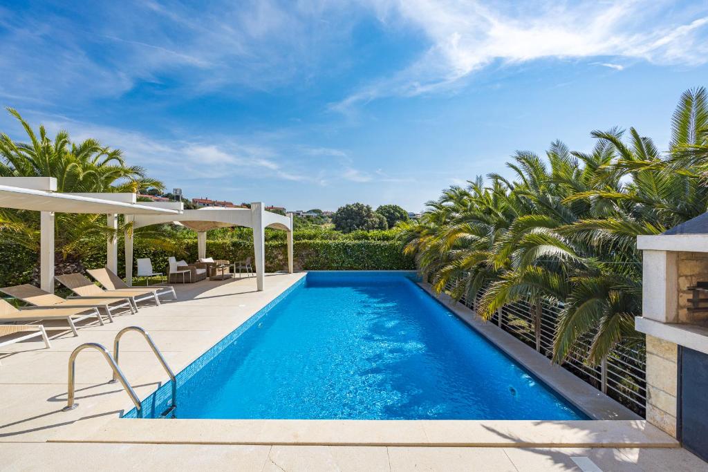 a swimming pool in a backyard with palm trees at Villa Laura in Pula