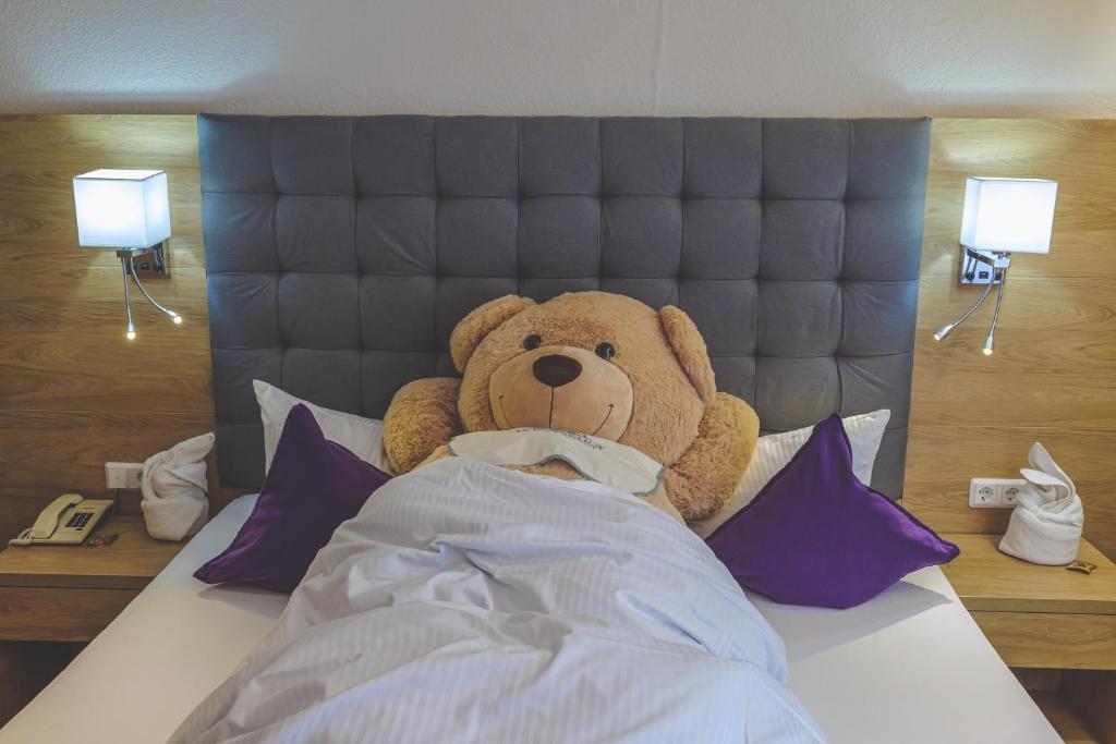 a large teddy bear sitting in the bed at Hotel Styrolerhof in Steeg
