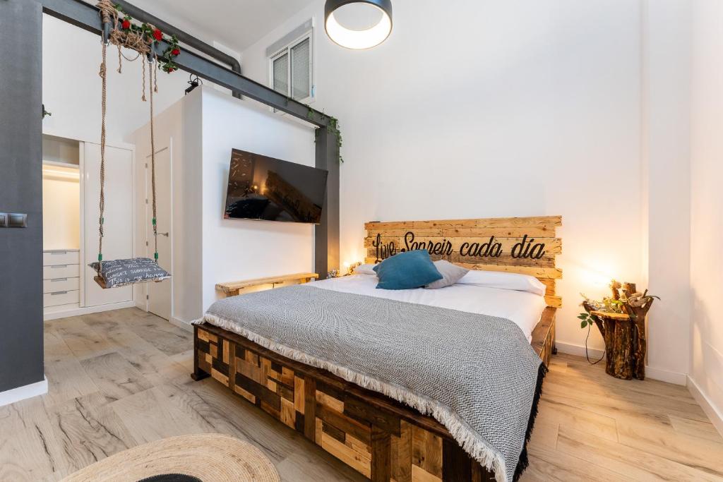 sypialnia z dużym łóżkiem z drewnianym zagłówkiem w obiekcie MalagaSuite Huelin Urban Estudio w Maladze