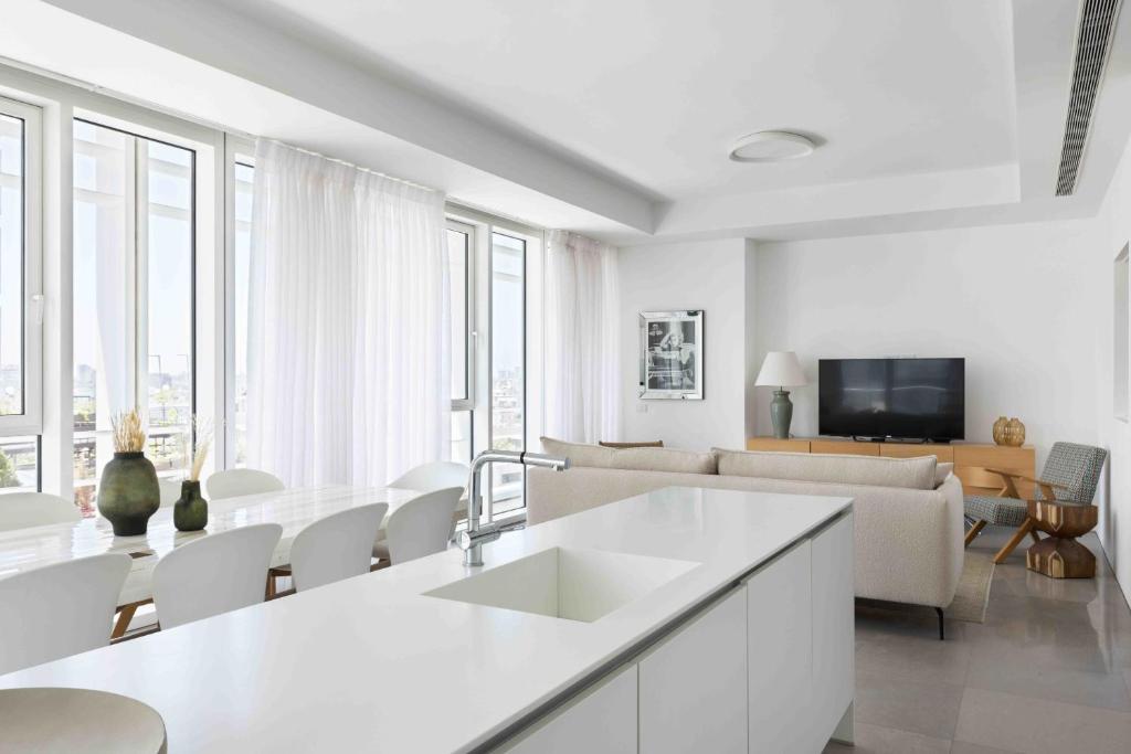 cocina blanca y sala de estar con sofá en Exclusive Meier on Rothschild by Five Stay en Tel Aviv