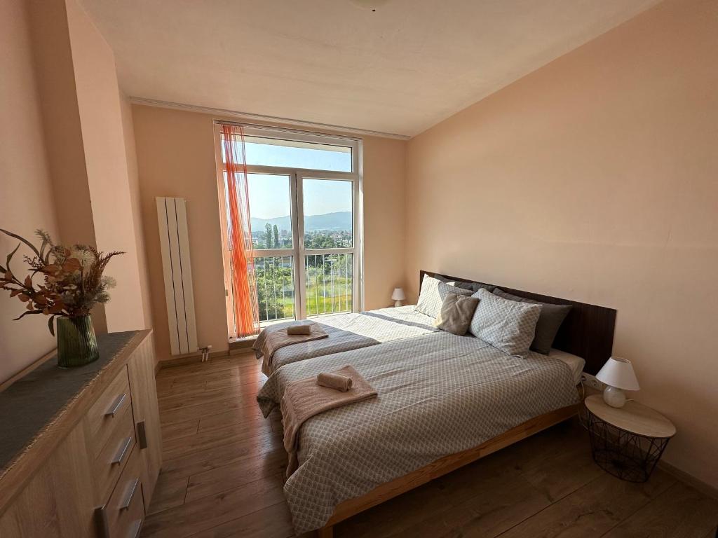 a bedroom with a bed and a large window at INTER EXPO APARTMENT in Sofia