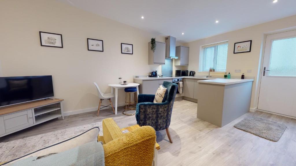 a kitchen and living room with a couch and chairs at Primera Barn in Witney
